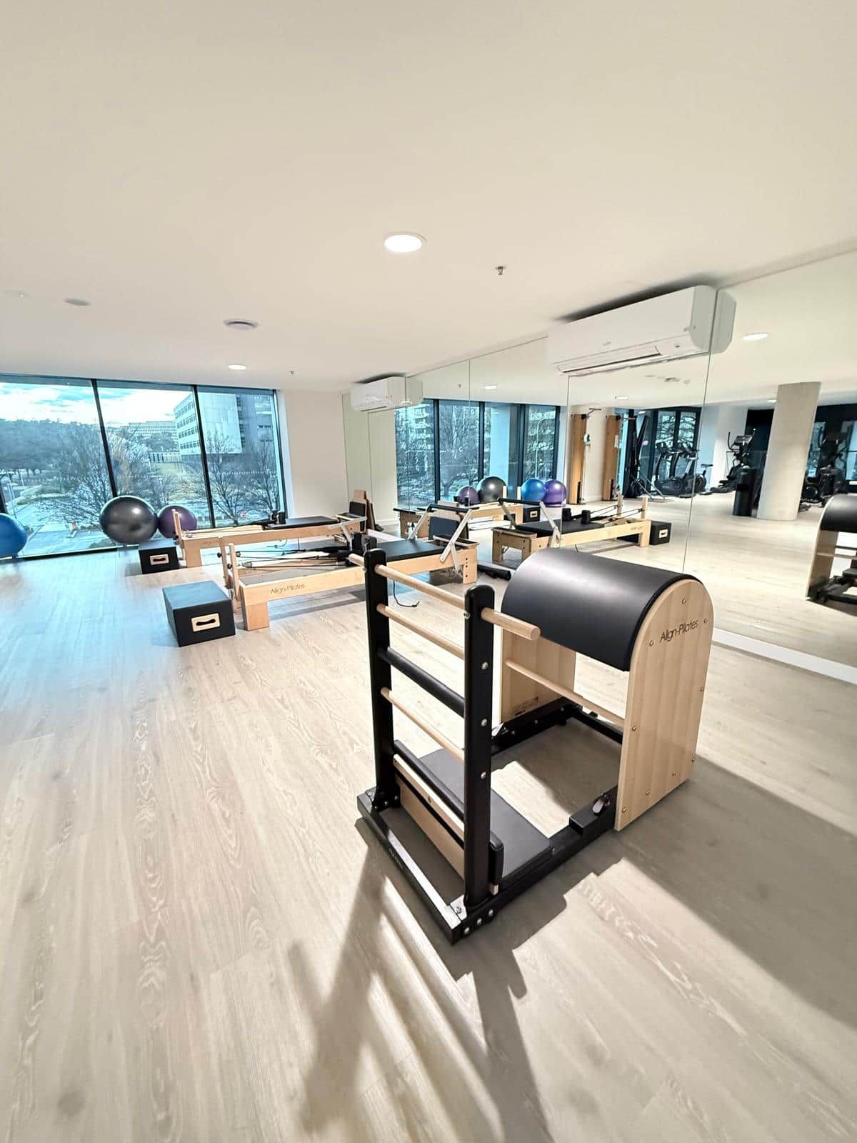 A gym with exercise equipment, large windows, and a view of the outdoors.