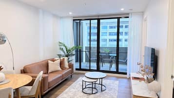 A modern living room with a brown leather sofa, a round dining table, and a small coffee table.