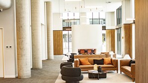 A spacious lobby with a modern design, featuring a central seating area with sofas and a coffee table, large windows, and a high ceiling with hanging lights. - The Eastbourne Premium 2BR Central Canberra (Parkes)