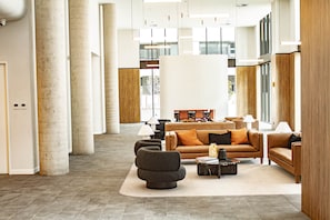 A spacious lobby with a modern design, featuring a central seating area with sofas and a coffee table, large windows, and a high ceiling with hanging lights. - The Eastbourne Premium 2BR Central Canberra (Parkes)