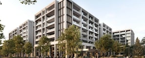 A multi-story building with balconies, a central entrance, and surrounding trees. - The Eastbourne Premium 2BR Central Canberra (Parkes)