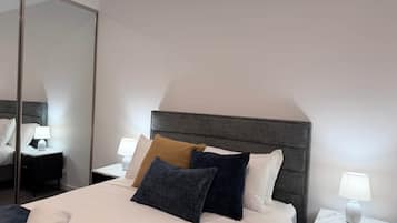 A hotel room with a bed, nightstands, a lamp, and a mirror.