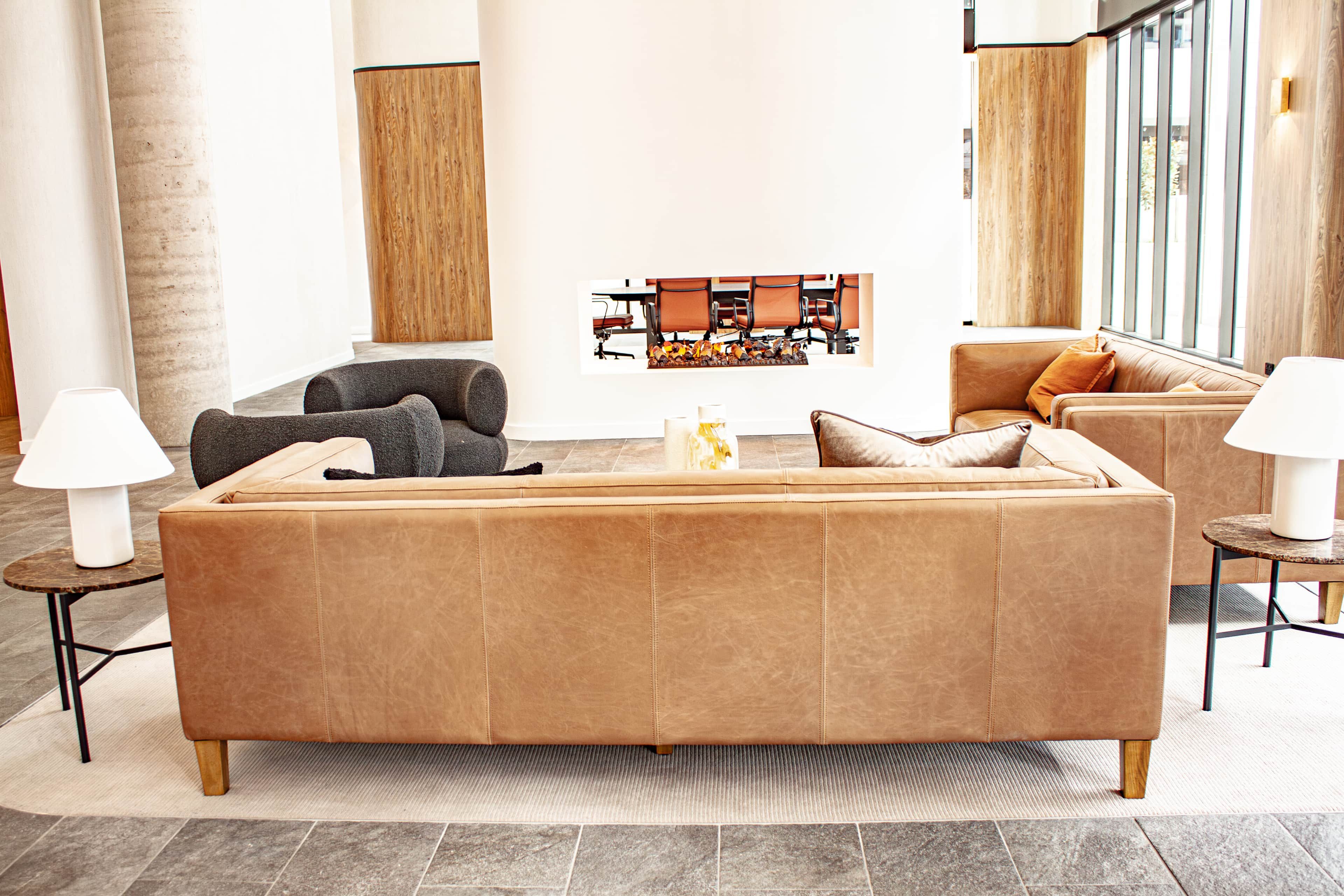 A modern living room with a large sofa, two armchairs, a coffee table, and a fireplace.