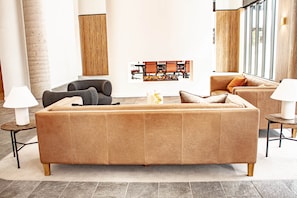 Una sala de estar moderna con un sofá grande, dos sillones, una mesa de centro y una chimenea.