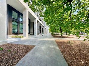 A modern building with a covered walkway, surrounded by trees and landscaped areas.