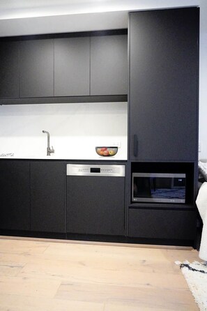 A modern kitchen with a built-in dishwasher, a microwave, and a sink. - Stylish, Cosy City Retreat in Reid Canberra (Reid)