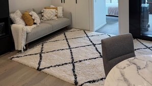 A modern living room with a grey sofa, a white rug, and a marble coffee table. - Stylish, Cosy City Retreat in Reid Canberra (Reid)