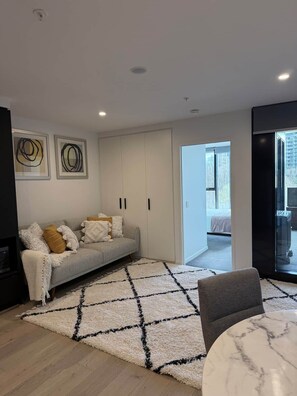 A modern living room with a grey sofa, a white rug, and a marble coffee table. - Stylish, Cosy City Retreat in Reid Canberra (Reid)