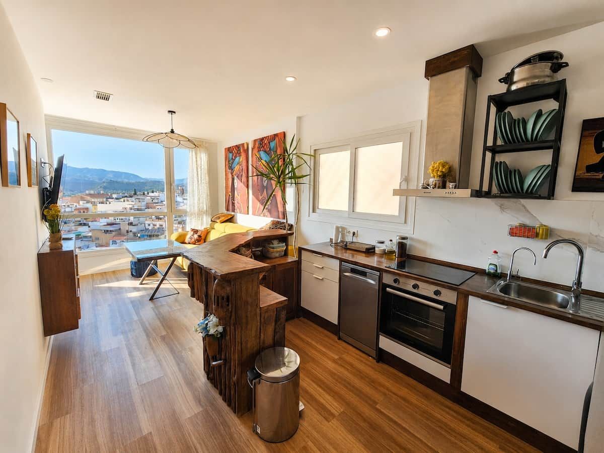 Eine moderne Küche mit einer Holztischinsel, Edelstahlgeräten und Blick auf die Stadt.