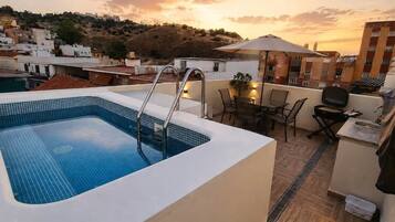Una piscina sul tetto con vista sulla città al tramonto.