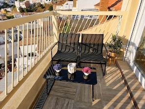 Ein Balkon mit zwei Stühlen, einem kleinen Tisch und Topfpflanzen.