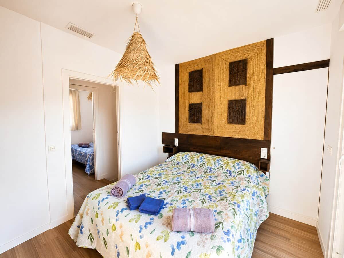 Ein Schlafzimmer mit einem Bett, einer Pendelleuchte und einem hölzernen Kopfteil.