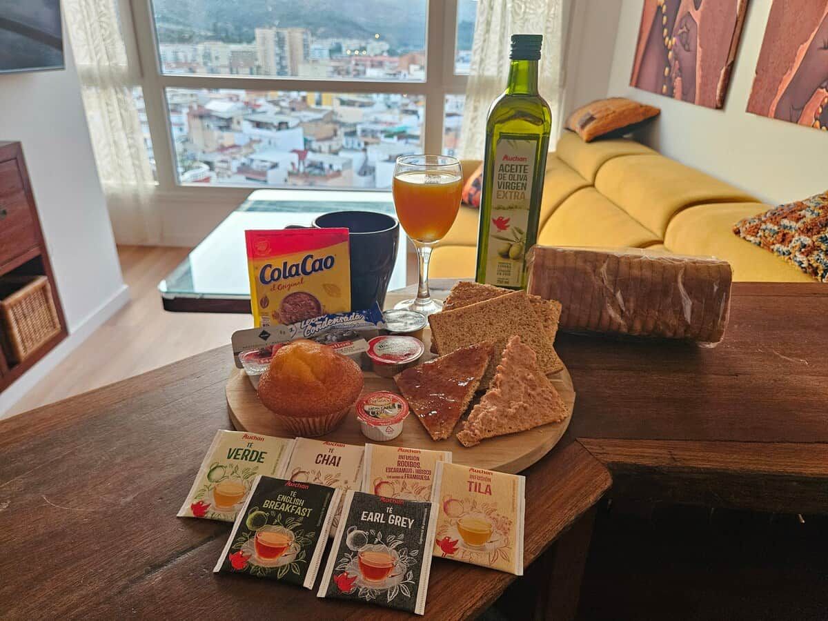 Ein Frühstückstisch mit Olivenöl, Brot, Muffins und Kaffeepäckchen.