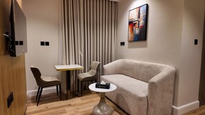 Habitació d'hotel moderna amb un sofà, dues cadires, una taula petita i un quadre al mur.