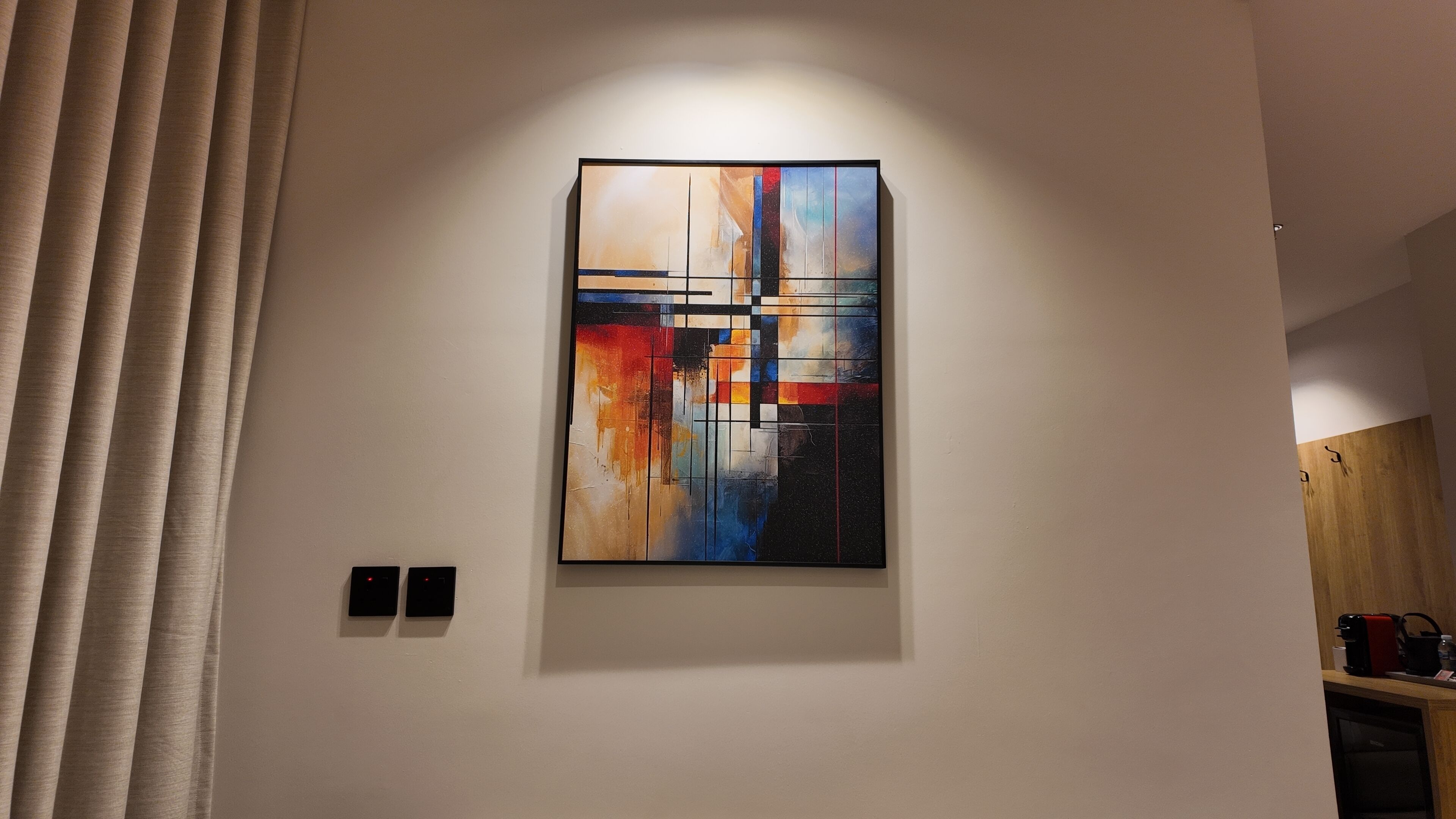A modern interior with a large abstract painting on the wall, a wooden cabinet, and a black electrical outlet.