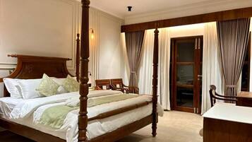 A four-poster bed with a wooden headboard, a ceiling fan, and a view of a sliding glass door leading to a balcony.