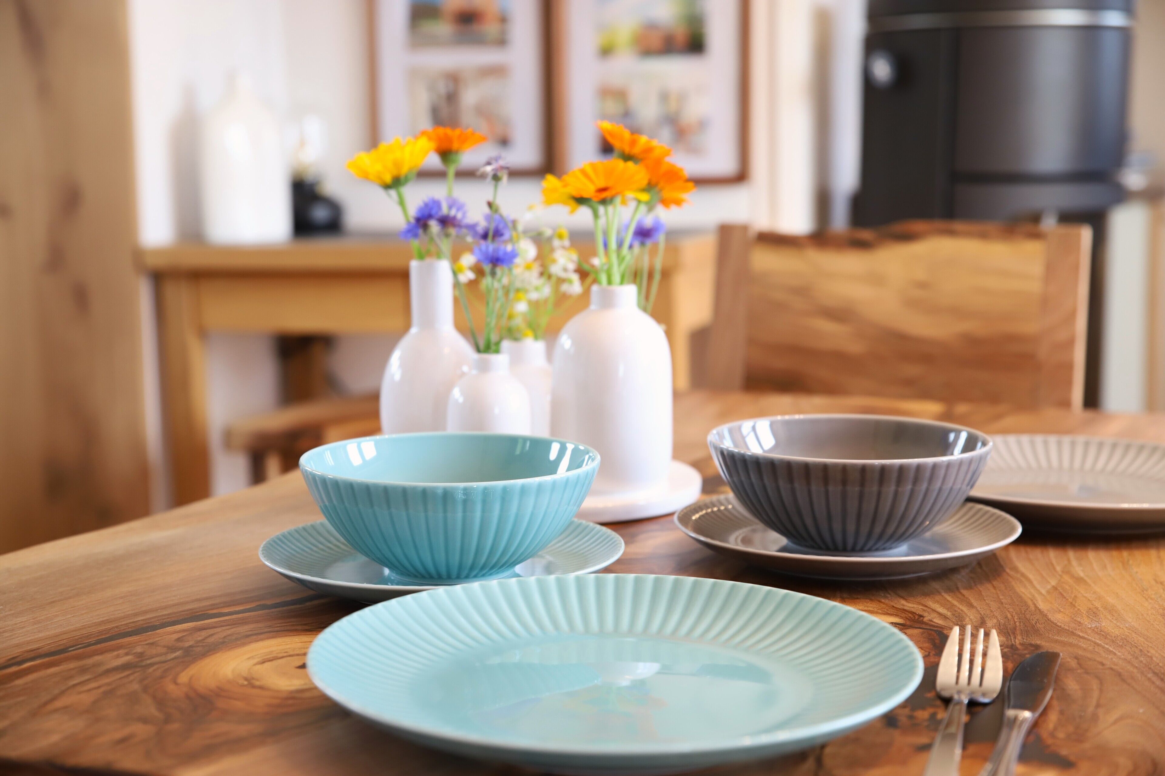 Een eettafel met een blauwe kom, een grijze kom en een bord, inclusief een vork en mes.