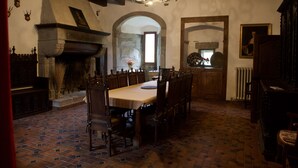 A dining room with a long table and chairs, a fireplace, and a chandelier.