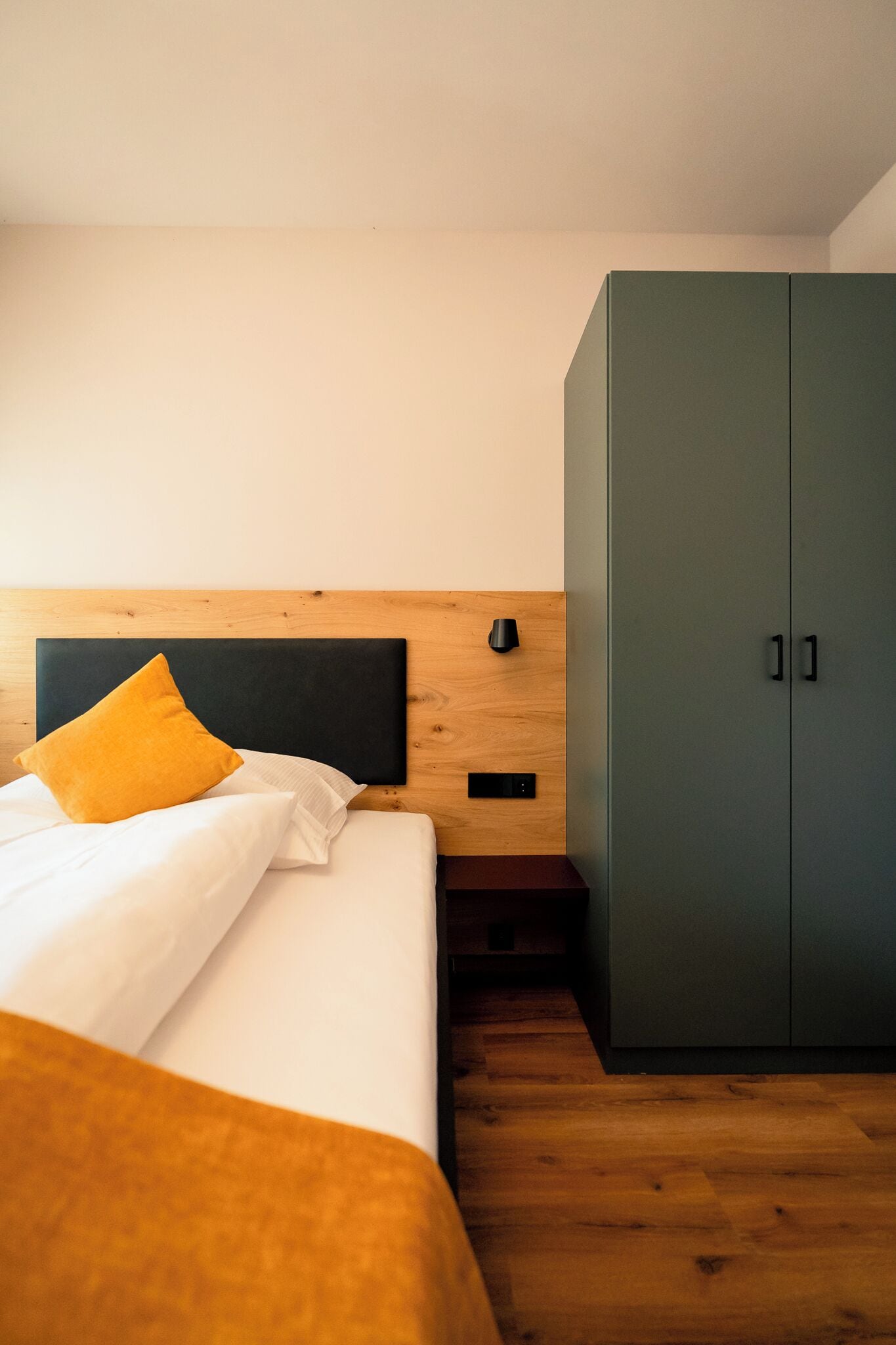 Ein Schlafzimmer mit einem Bett, einem Holzkopfende, einem Kleiderschrank und einem Nachttisch.