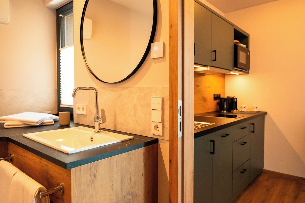 A modern bathroom with a marble sink, a large mirror, and wooden flooring.