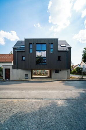 A modern two-story building with a flat roof, large windows, and a visible garage entrance.