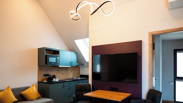 Un espace de vie moderne comprenant un coin repas, une cuisine et un grand téléviseur fixé au mur.