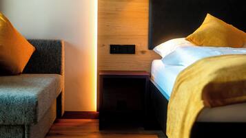 A modern bedroom with a wooden headboard, a bedside table, and a sofa.