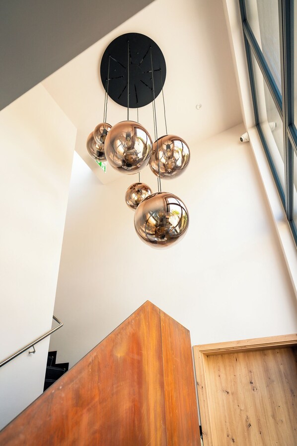 A modern interior with a wooden staircase and a ceiling-mounted spherical light fixture.