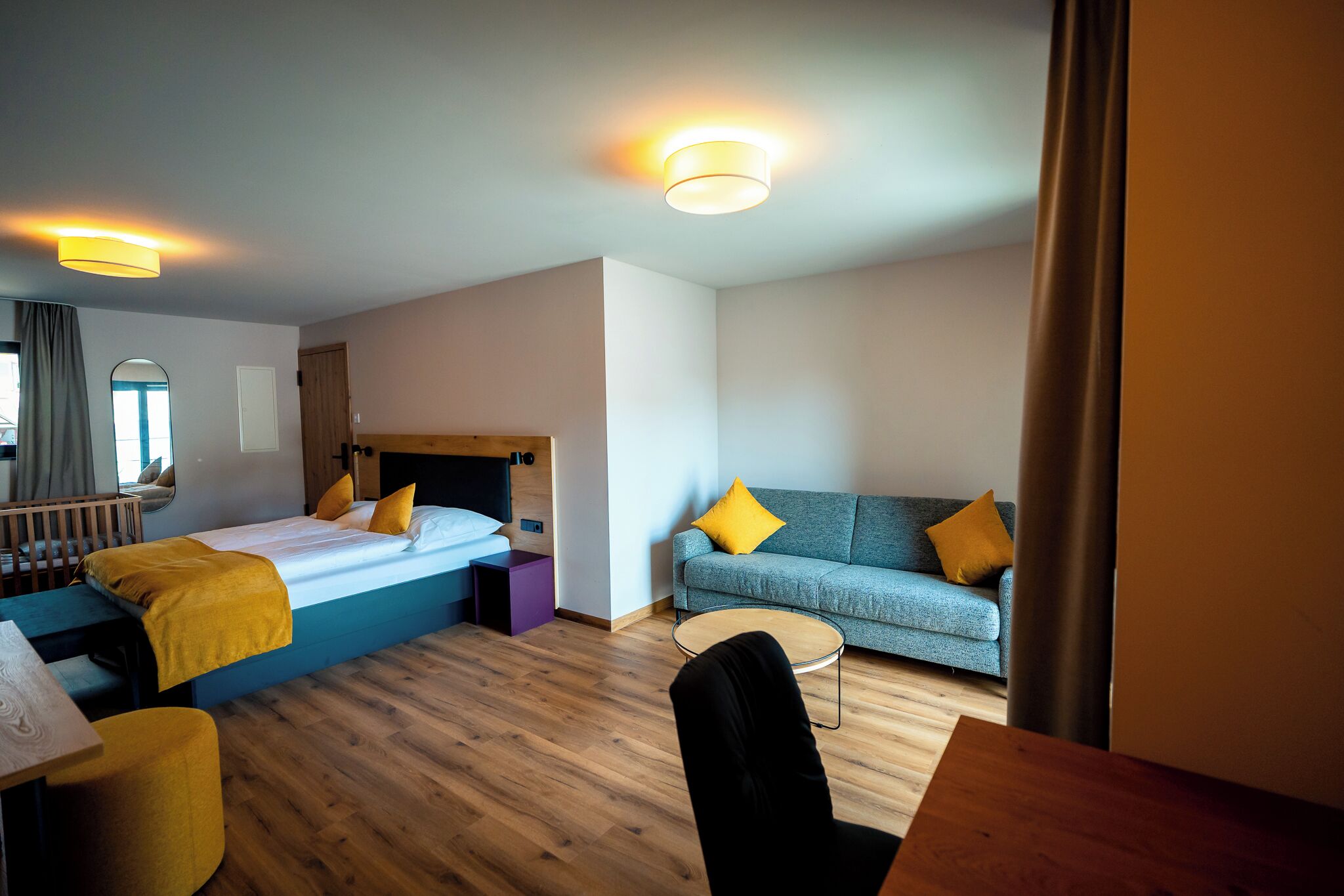 Una habitación de hotel con cama, sofá, una mesita y una silla.