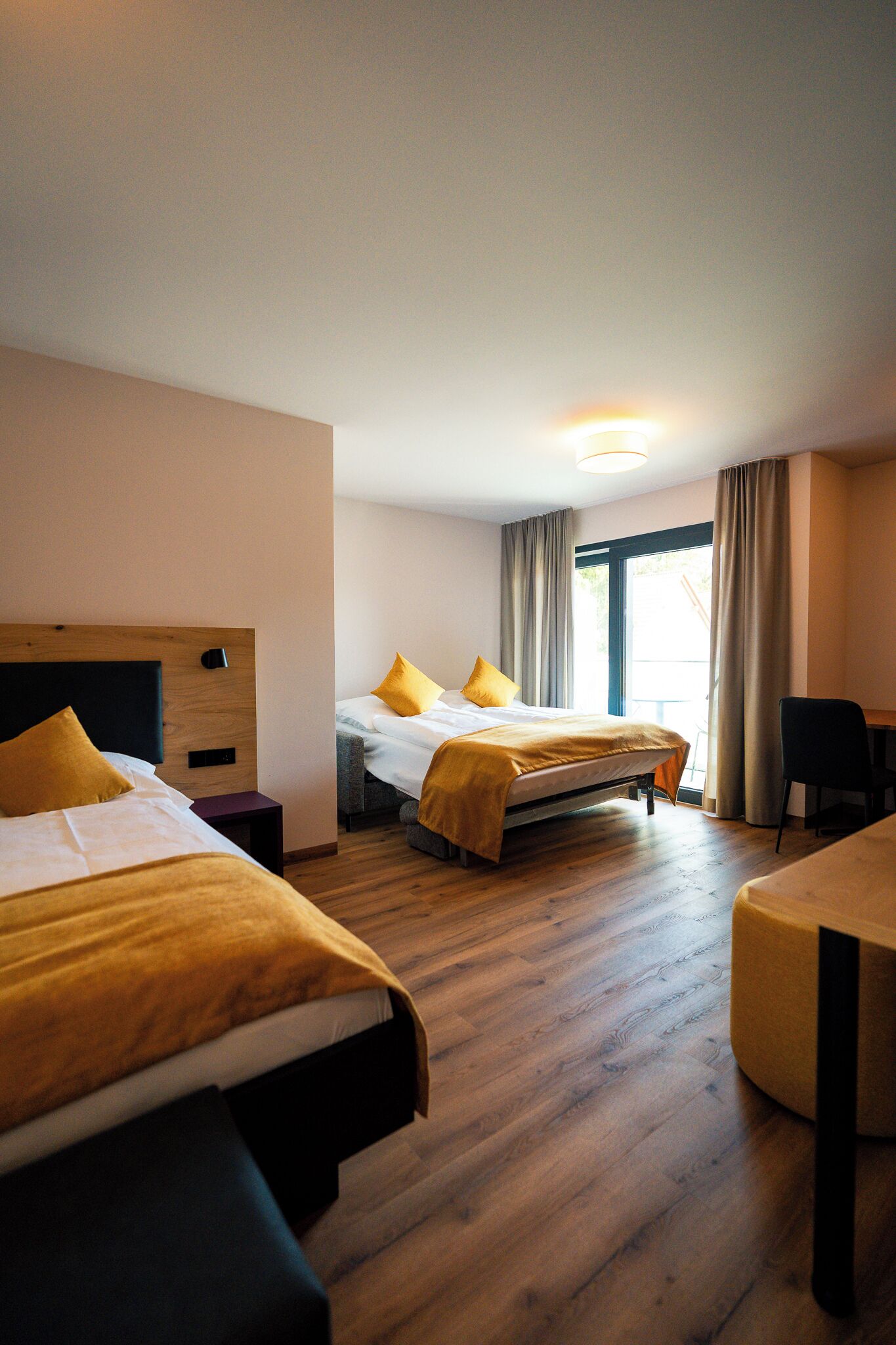 Ett hotellrum med två sängar, ett skrivbord och en stol.