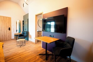 A modern living room with a flat-screen TV, a wooden table, and two chairs. - Adler Apartments  (Erbach)