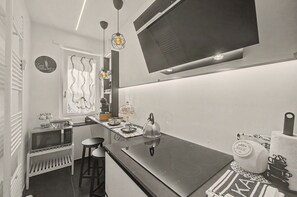 A modern kitchen with a flat-screen TV mounted above the counter, a microwave, and a kettle on the countertop.