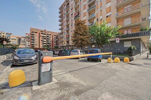 A multi-story residential building with balconies and a gated parking area.