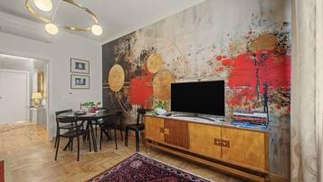 A modern living room with a large abstract painting, a flat-screen TV, and a wooden cabinet.