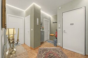 A hallway with a glass table, a candelabra, a rug, and a door with a fire extinguisher. - Casa Simone Apartment near Inalpi Arena, Wi-Fi and Air Conditioning (Torino)