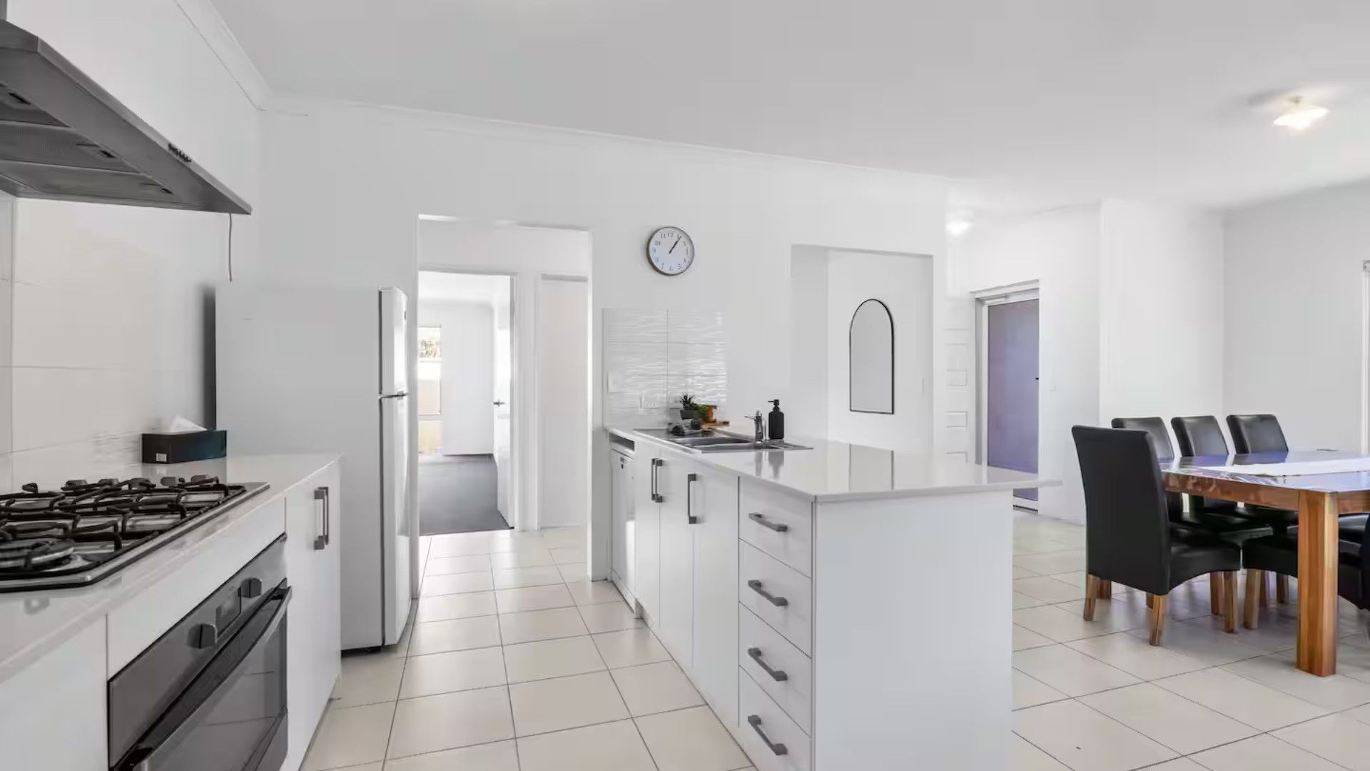 Una cucina moderna con piano cottura a gas, frigorifero e zona pranzo con tavolo e sedie.