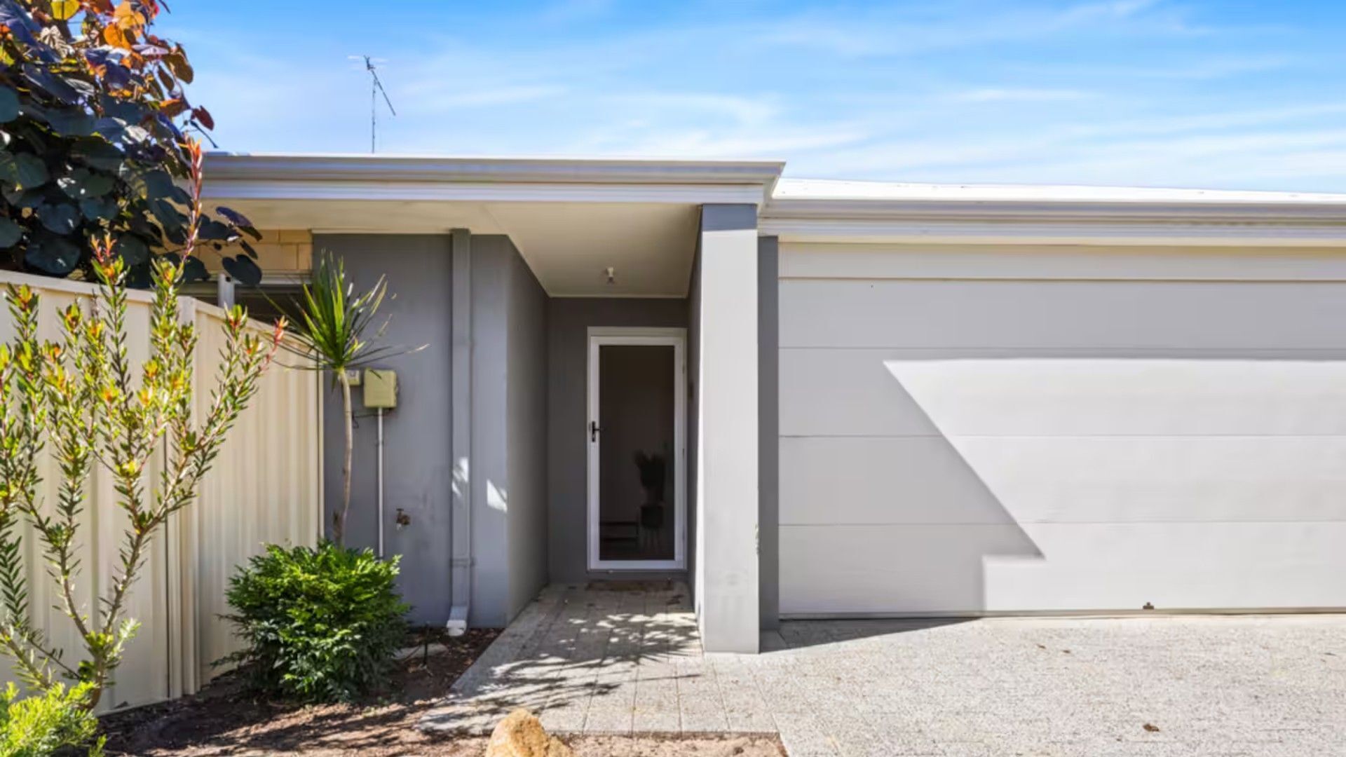 A modern single-story house with a garage, a small front yard, and a clear sky.