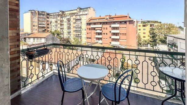 A balcony with a round table and two chairs, overlooking a cityscape with multi-story buildings. - No. 9 - Spacious 140 m² Apartment in Mestre (Mestre)