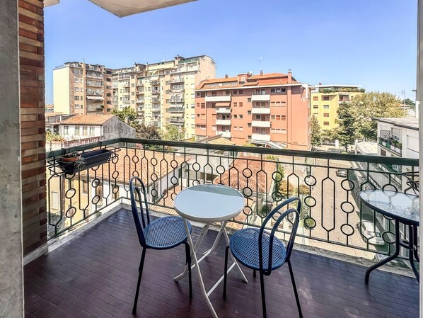 A balcony with a round table and two chairs, overlooking a cityscape with multi-story buildings. - No. 9 - Spacious 140 m² Apartment in Mestre (Mestre)