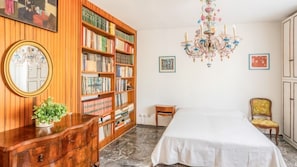 Une chambre à coucher avec une grande bibliothèque, un lit, une chaise et un lustre.