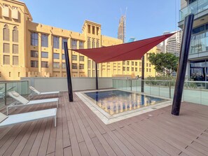 A rooftop pool area with lounge chairs and a red canopy. - Spacious 2Bedroom+ Maid room with Burj Khalifa View (دبي)