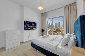 A modern bedroom with a large bed, a TV mounted on the wall, and a city view through the window. - Spacious 2Bedroom+ Maid room with Burj Khalifa View (دبي)
