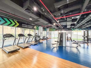 A gym with treadmills, weight machines, and a blue floor. - Spacious 2Bedroom+ Maid room with Burj Khalifa View (دبي)