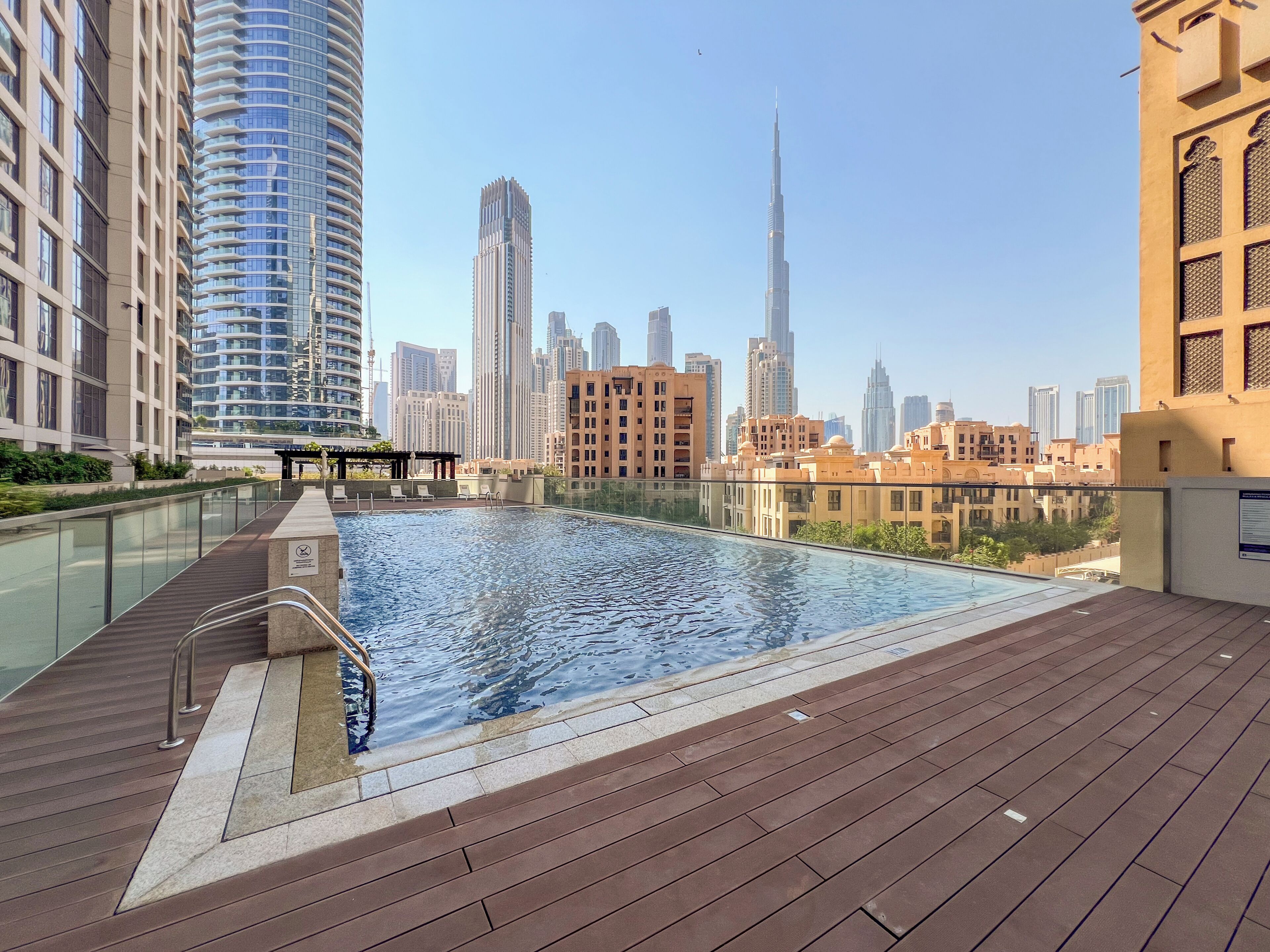 A rooftop swimming pool with a city skyline in the background.