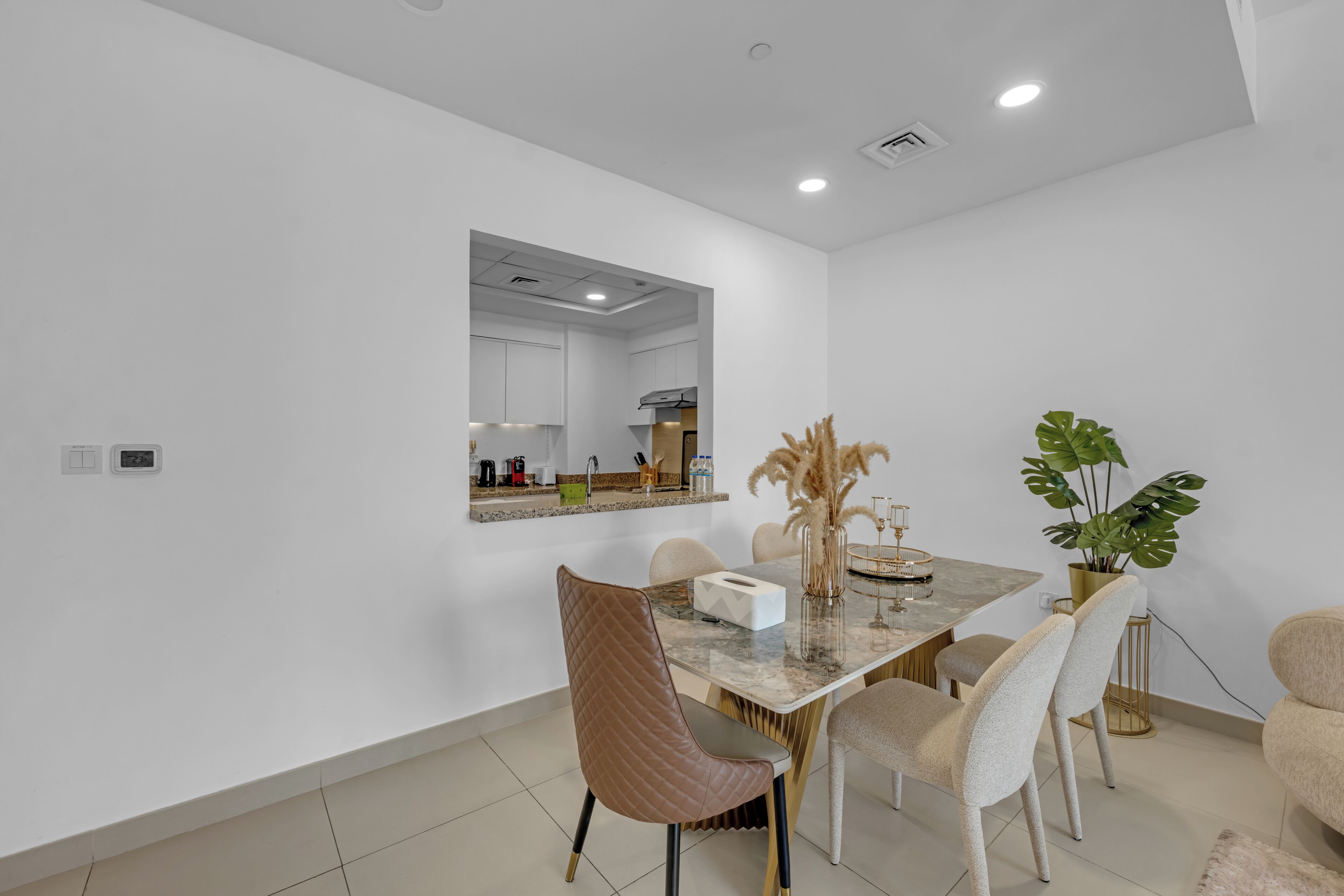 A modern dining area with a marble table, leather chairs, and a mirror above the counter.