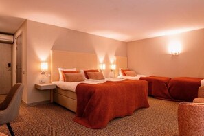 Habitación de hotel con una cama grande, dos mesitas de noche, una silla y piso alfombrado.