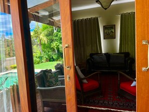 A room with a red carpet, a sofa, and a view of a pool and greenery.