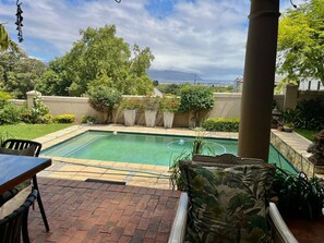Piscina retangular com área de estar ao redor, uma mesa e cadeiras.