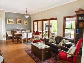 Un salon comprenant un canapé, des fauteuils, une table basse et un coin repas avec une table et des chaises.