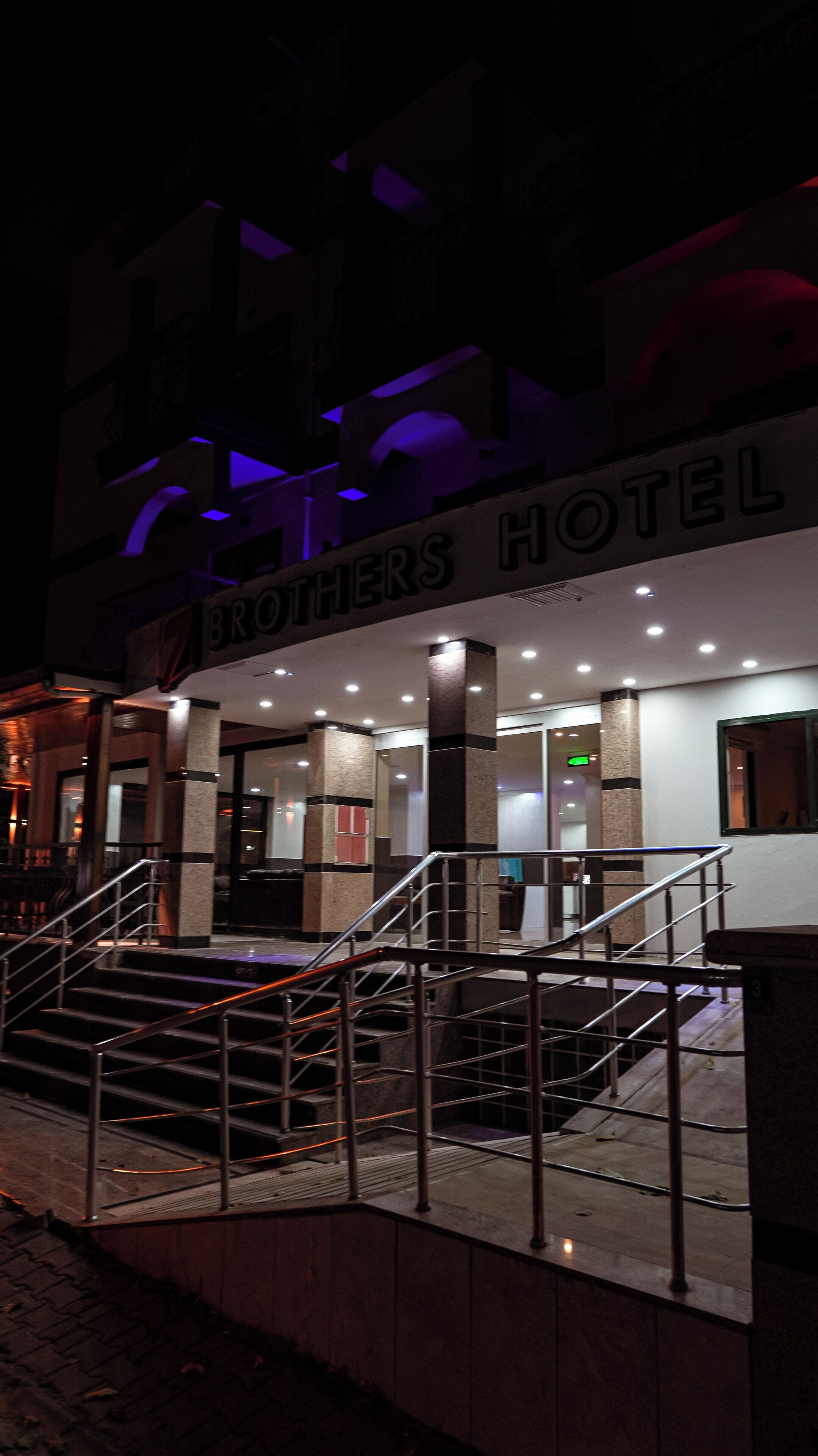 Entrada de un hotel con un letrero que dice 'BROTHERS HOTEL' y una escalera que lleva a la entrada.